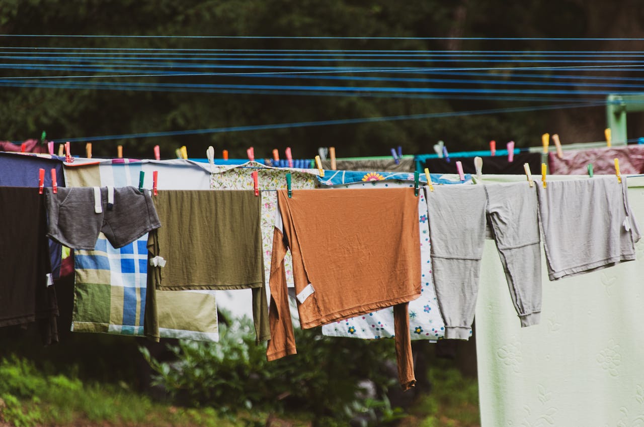 Vibrant clothes hanging on a clothesline outdoors in a lush green setting, creating a rustic charm.